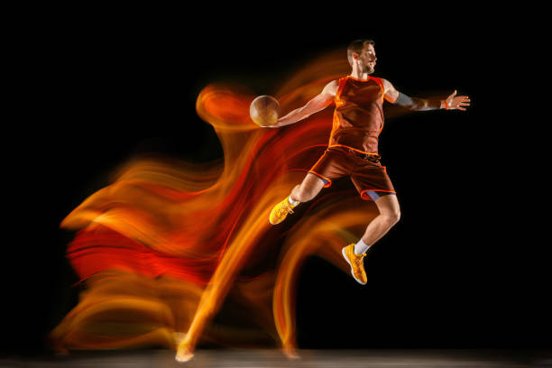 istock Young caucasian basketball player against dark background in mixed light 1170916478