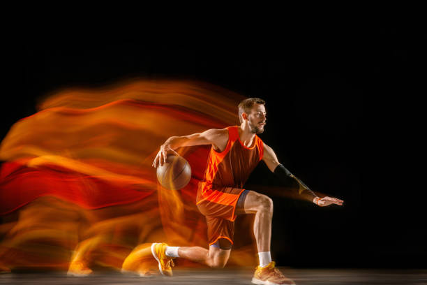 istock Young caucasian basketball player against dark background in mixed light 1170916493