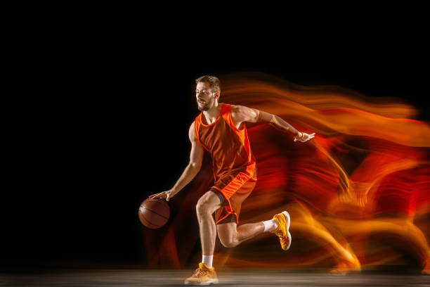 istock Young caucasian basketball player against dark background in mixed light 1170916513