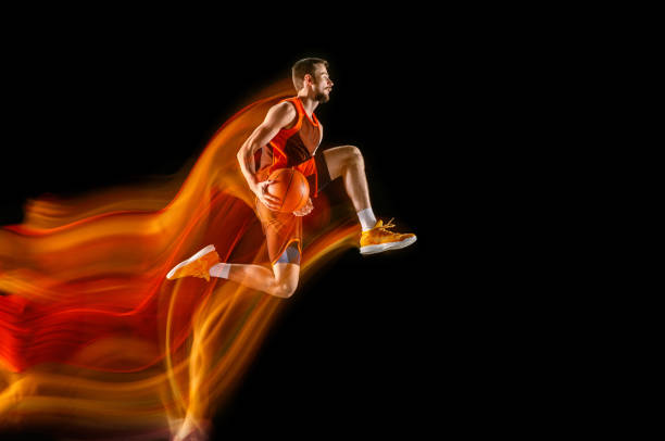 istock Young caucasian basketball player against dark background in mixed light 1170916515