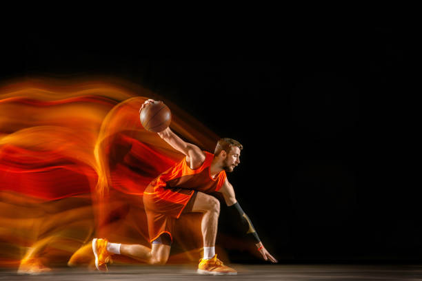 istock Young caucasian basketball player against dark background in mixed light 1170916533