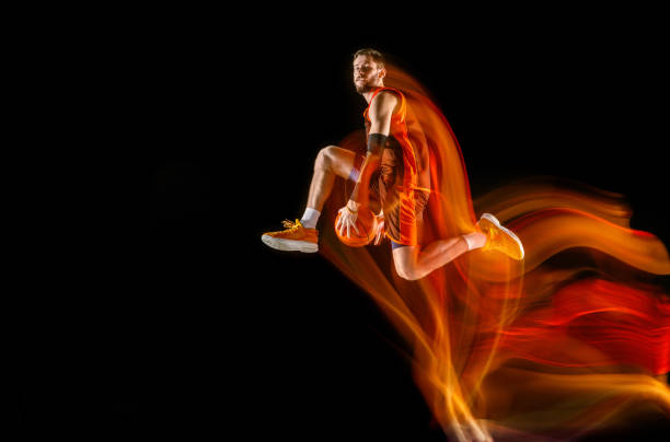 istock Young caucasian basketball player against dark background in mixed light 1170916560