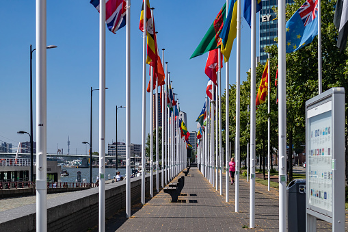 Rotterdam, Netherlands - June 28, 2019: Quay pavement with rows of various waving national flags at flagpoles