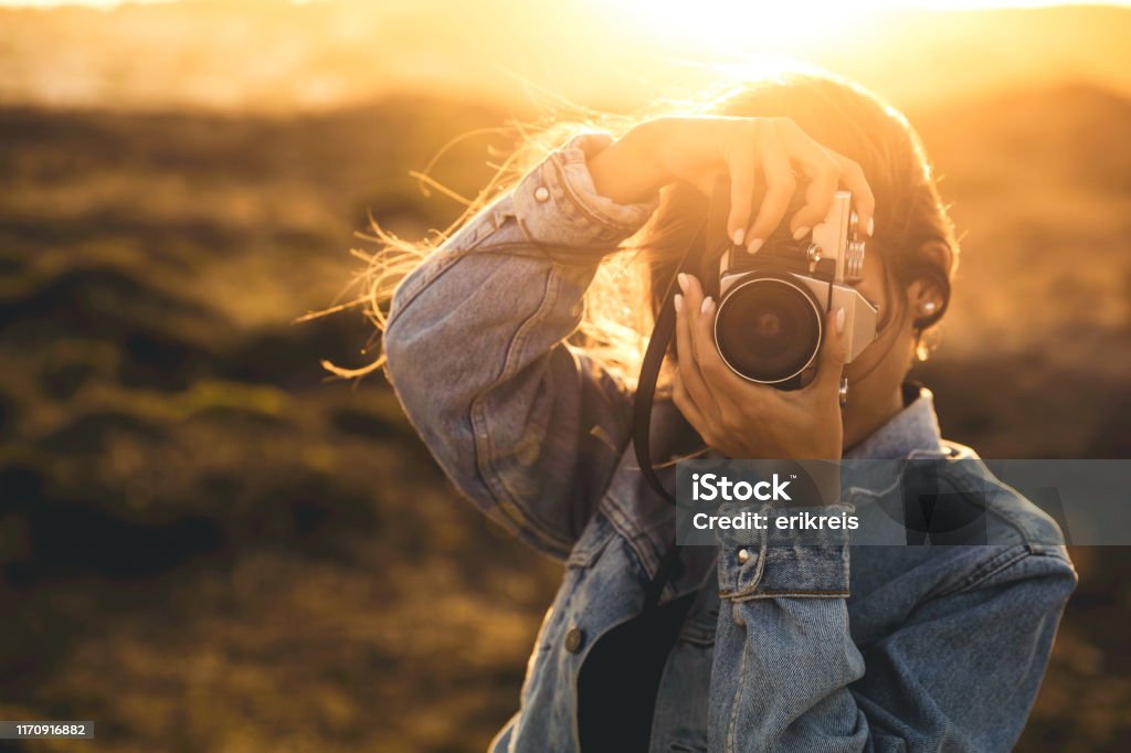 Woman Taking Picture Outdoors Beautiful woman taking picture outdoors with a analog camera Photographer Stock Photo