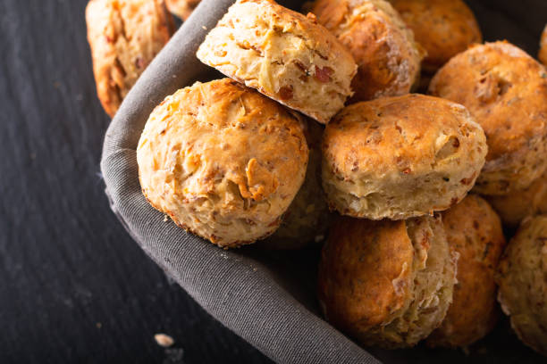 conceito do alimento fresco cozido caseiro amanteigado, presunto salgado e scones do queijo no fundo preto - comida salgada - fotografias e filmes do acervo