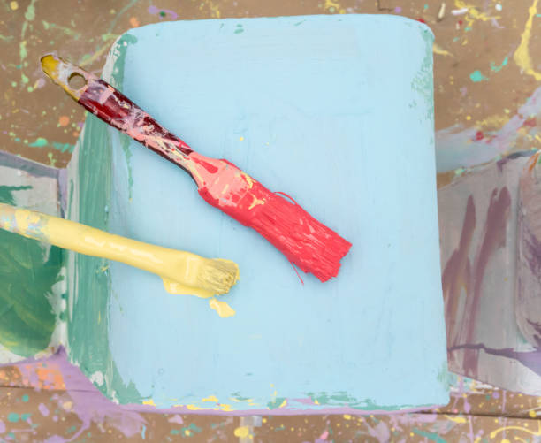 istock Two paint brushes with red and yellow color on light blue background. 1170921846