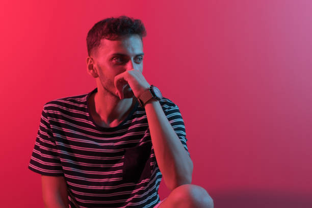istock Young handsome man sitting on chair by neon lights. 1170922139