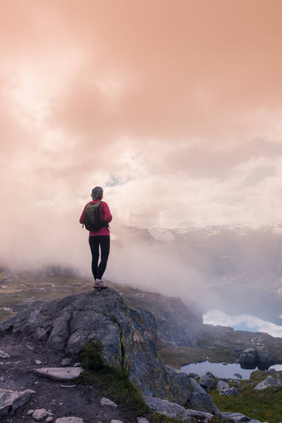 istock Young woman with backpack standing on fjord coast 1170922145