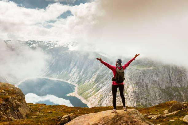 istock Young woman with backpack standing on fjord coast 1170922456