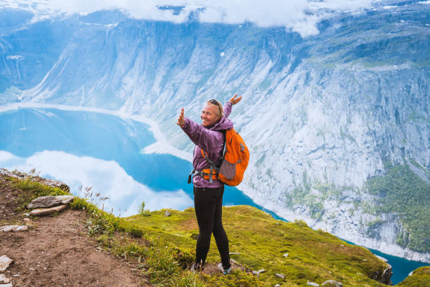 istock Young woman with backpack standing on fjord coast 1170923207