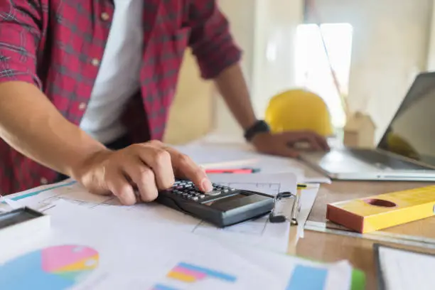 architect man working with laptop and blueprints, architectural plan with calculator in loft office,Building Design,Home or house town planning,engineering tool for sketching a construction project