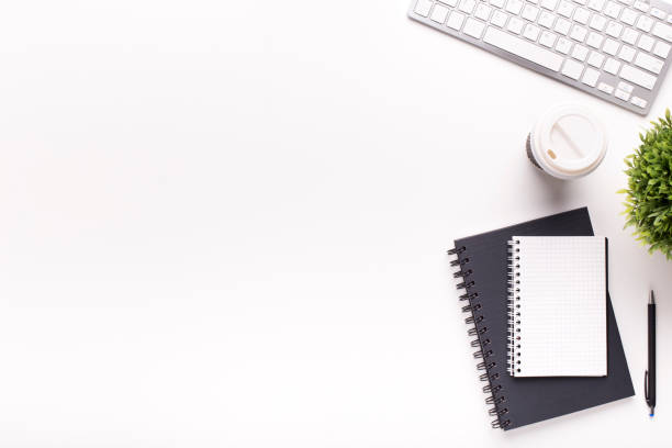 Black and white notepads, keyboard and plant on office table