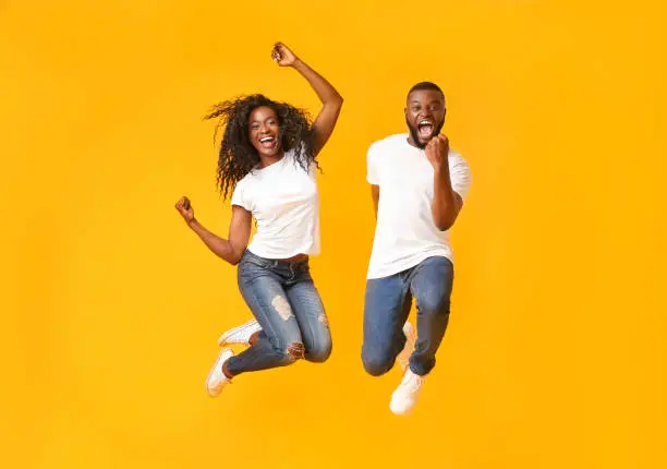 Photo of Joyful black couple jumping up and down