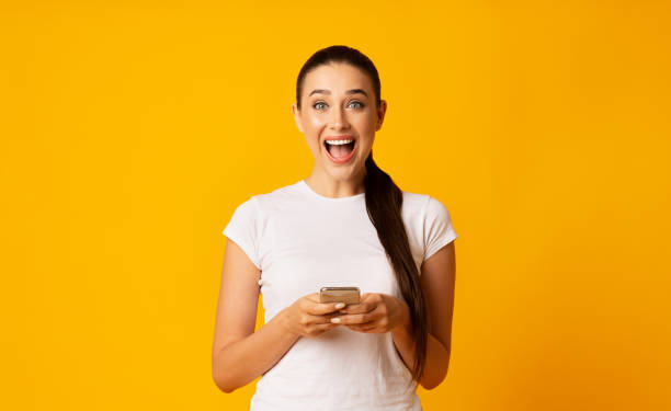 istock Excited Woman Browsing On Smartphone Over Yellow Background, 1170923849