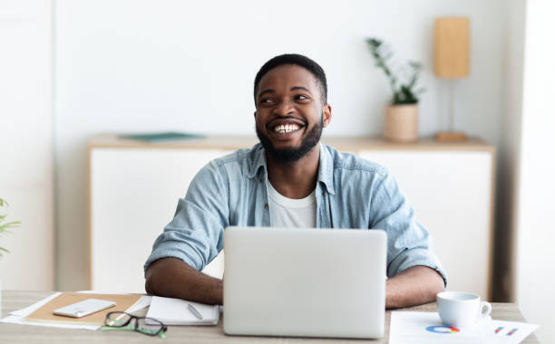 istock Working with fun. Smiling african guy sitting at workplace 1170924885