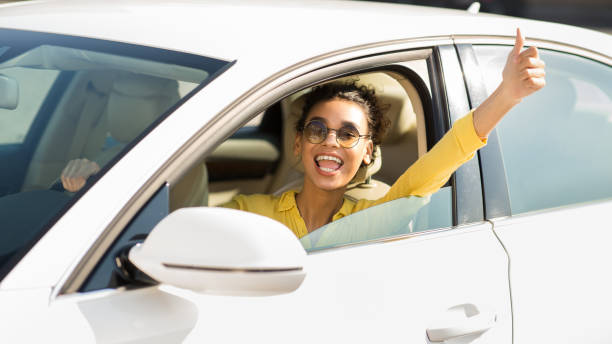 nuovo proprietario di un'auto. donna felice che mostra il pollice in su - car african descent shopping car dealership foto e immagini stock