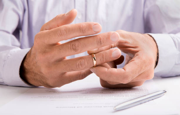 istock Man in suit removing his wedding ring from finger 1170925286
