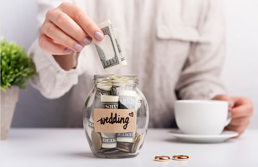 Wedding savings. Woman throwing dollars in jar with money for wedding