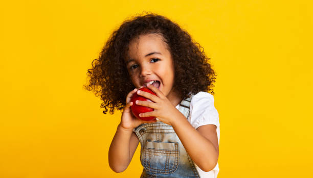 ビタミンスナック赤いリンゴを噛む小さな女の子 - child eating apple fruit ストックフォトと画像