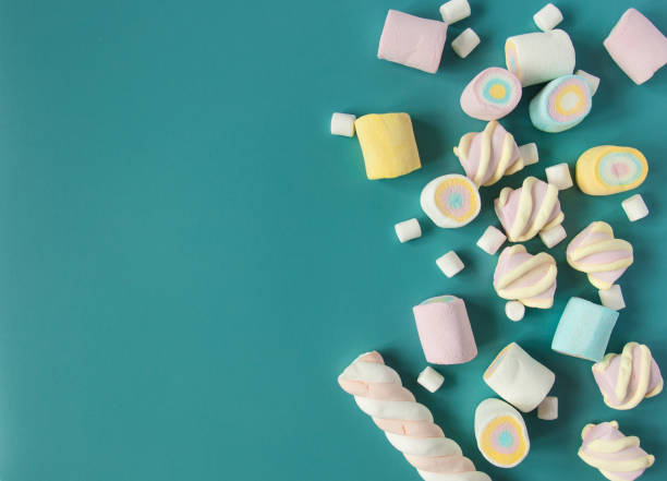 istock Natural marshmallows sweets on a blue background. Airy multicolored marshmallows sprinkled on the table. 1170933306