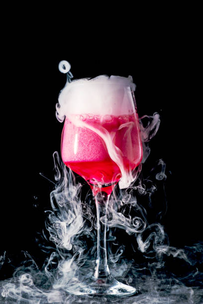 Green liquid in wine glass with fog and smoke pouring out.