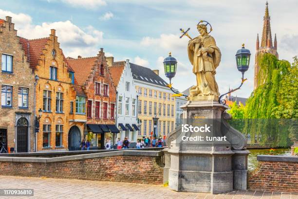 Traditional Riverside Buildings St John Of Nepomuk Statue And Tower Of Church Of Our Lady In Brugge Belgium Stock Photo - Download Image Now