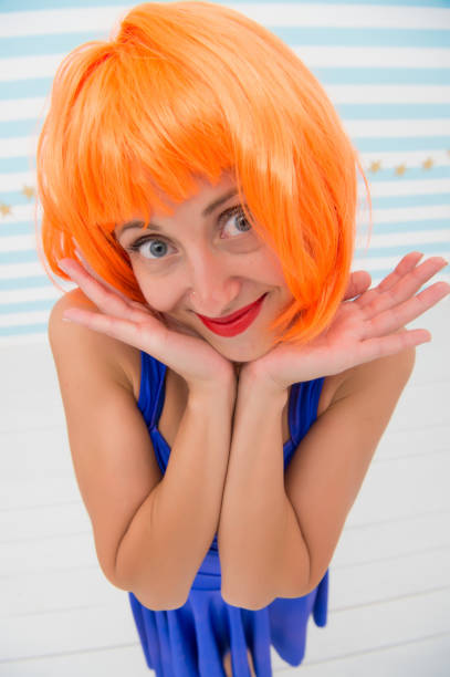 istock She likes bright outfit. Lady actress practicing performance. Girl posing striped background of studio. Lady red ginger wig posing in blue dress. Comic actress concept. Woman playful mood having fun 1170938099