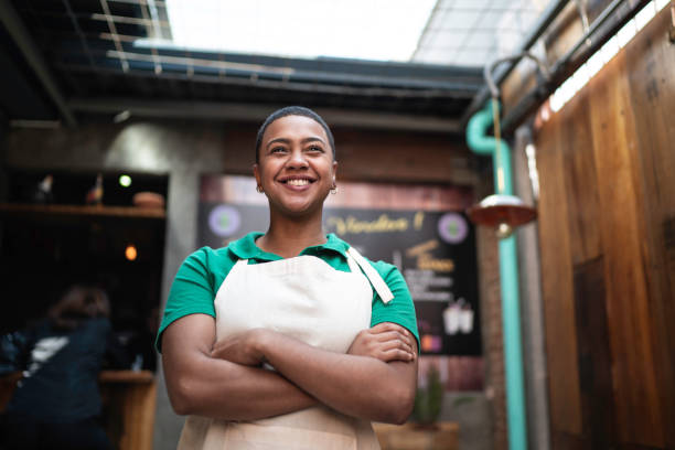 портрет молодого владельца бизнеса, стоящего перед рестораном со скрещенными руками - owner small business restaurant african ethnicity стоковые фото и изображения