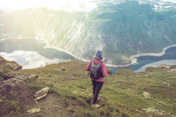 istock Young woman with backpack standing on fjord coast 1170938544
