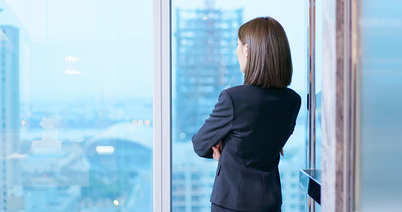 businesswoman look outside through the windor and ponder