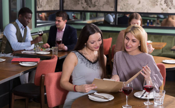 istock Two female friends with menu card in restaurant 1170949078