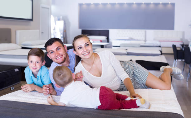 istock parents with two young sons testing mattress in store 1170949764