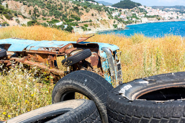 Abandoned overturned scrap yellow car in weed, Greece.