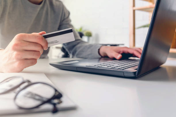 istock Man working on laptop computer while sitting on desk paying online with his credit card 1170951656