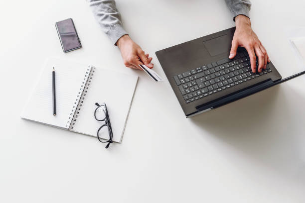 istock Man working on laptop computer while sitting on desk paying online with his credit card 1170952625