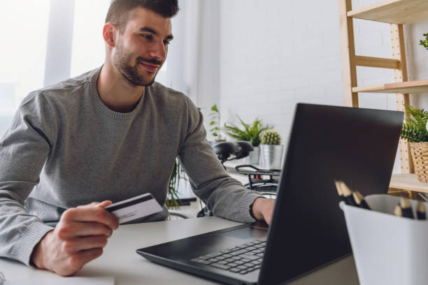 istock Man working on laptop computer while sitting on desk paying online with his credit card 1170952787