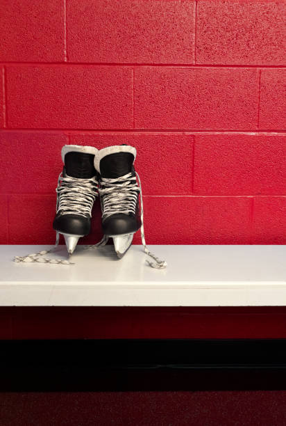 skate do hóquei sobre o banco branco no vestiário com fundo vermelho e espaço da cópia na posição do retrato. vista próxima - ice hockey ice team canada - fotografias e filmes do acervo