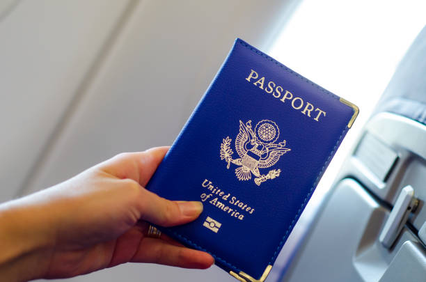istock Hand holding U.S. passport inside airplane cabin. 1170953730