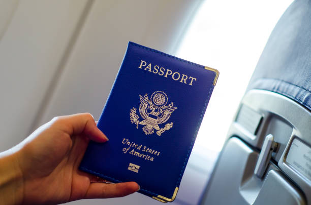 istock Hand holding U.S. passport inside airplane cabin. 1170953746
