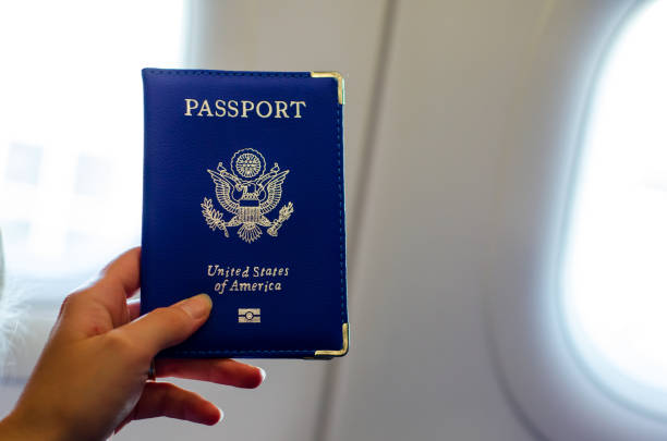 istock Hand holding U.S. passport inside airplane cabin. 1170953748