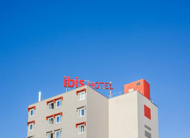 Ibis logo at hotel building in Beziers France Beziers, France - February 26, 2018: Ibis logo at hotel building located in Beziers, France. Bright blue sky with copy space background hotel ibis stock pictures, royalty-free photos & images