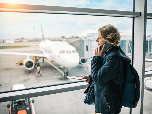 femme attendant son vol dans le salon d'aéroport - commercial airplane airport arrival departure board business travel photos et images de collection