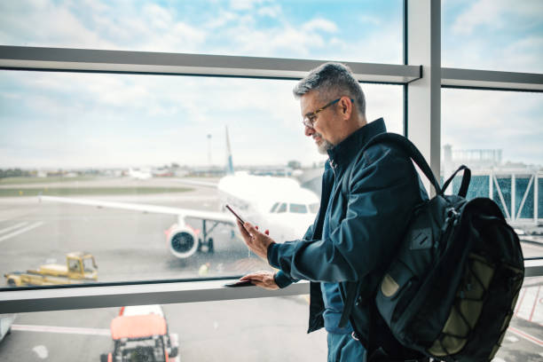 空港ラウンジでフライトを待っている男性 - arrival departure board airport travel business travel ストックフォトと画像