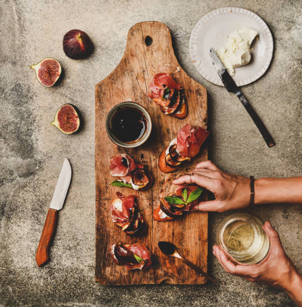 crostini mit schinken und glas wein in den händen der frau - crostini stock-fotos und bilder