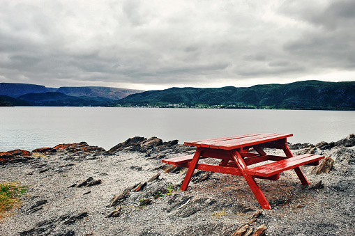 Beautiful landscape with a red picnic table on the pebbed beach at Bonne Bay , Norris Point, in Gros Morne National Park.