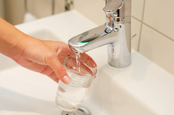 istock Female hands pouring water in glass cup 1170959032