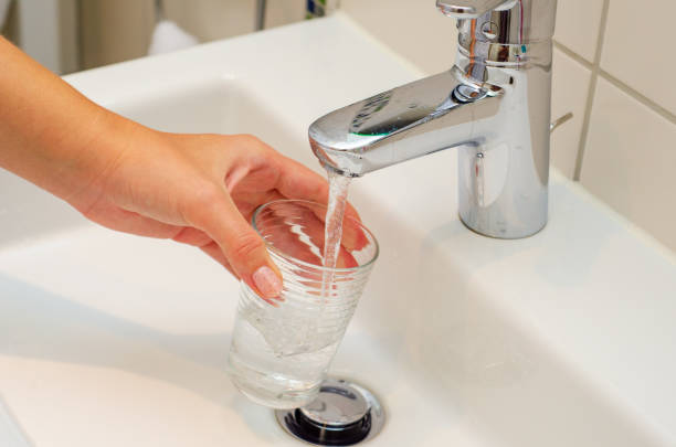 istock Female hands pouring water in glass cup 1170959045
