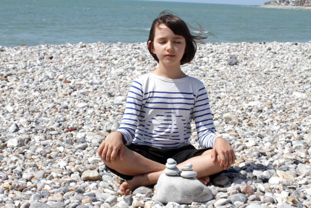istock calm child sitting with zen pebbles for mindfulness, water foreground 1170960163