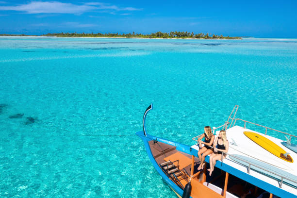 Two Women with Surfing Boards on Boat in Blue Ocean