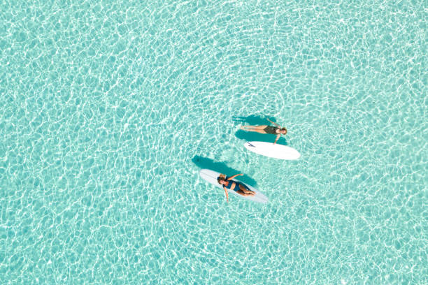 Two Women on Paddle Board in Blue Ocean Two Women on Paddle Board in Blue Ocean, Maldives lagoon stock pictures, royalty-free photos & images